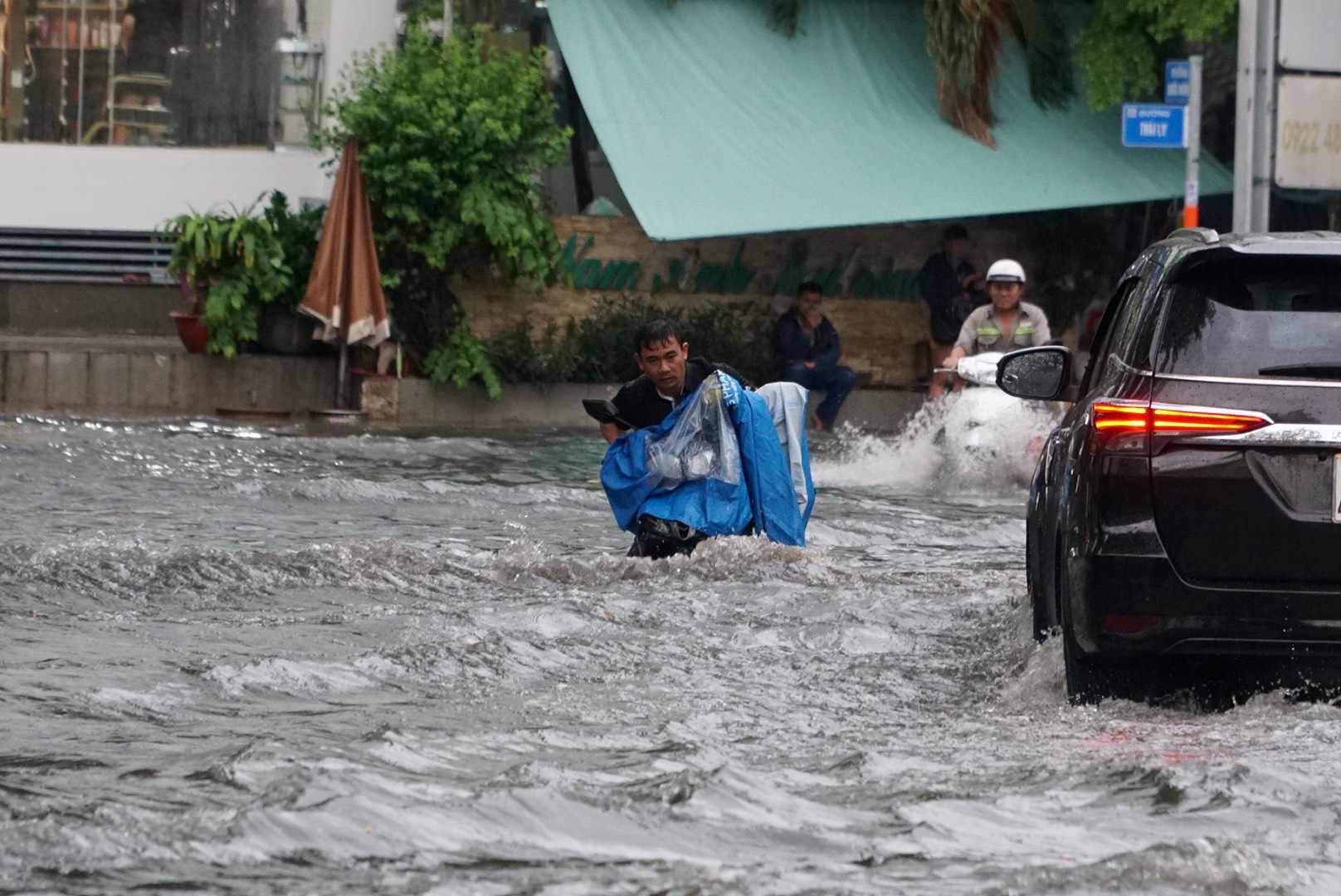 Ôtô chạy qua đoạn ngập tạo sóng gây khó khăn cho người đi xe máy.