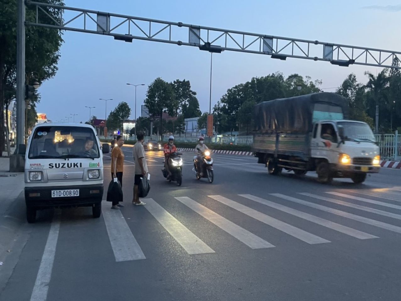 Hai bệnh nhân lớn tuổi phải băng qua đường nguy hiểm để đi mua vật tư y tế. Ảnh: Đình Trọng