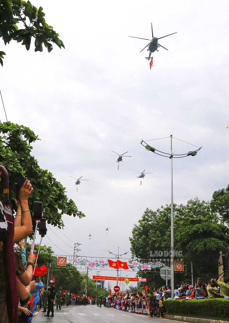 Các biên đội máy bay trực thăng mang theo cờ Đảng, cờ Tổ quốc bay lượn trên bầu trời.