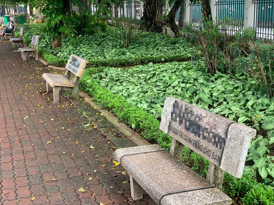 Hàng dài ghế đá trong công viên hồ Thành Công bị sơn các tên trang web nham nhở. Ảnh: Nhật Minh