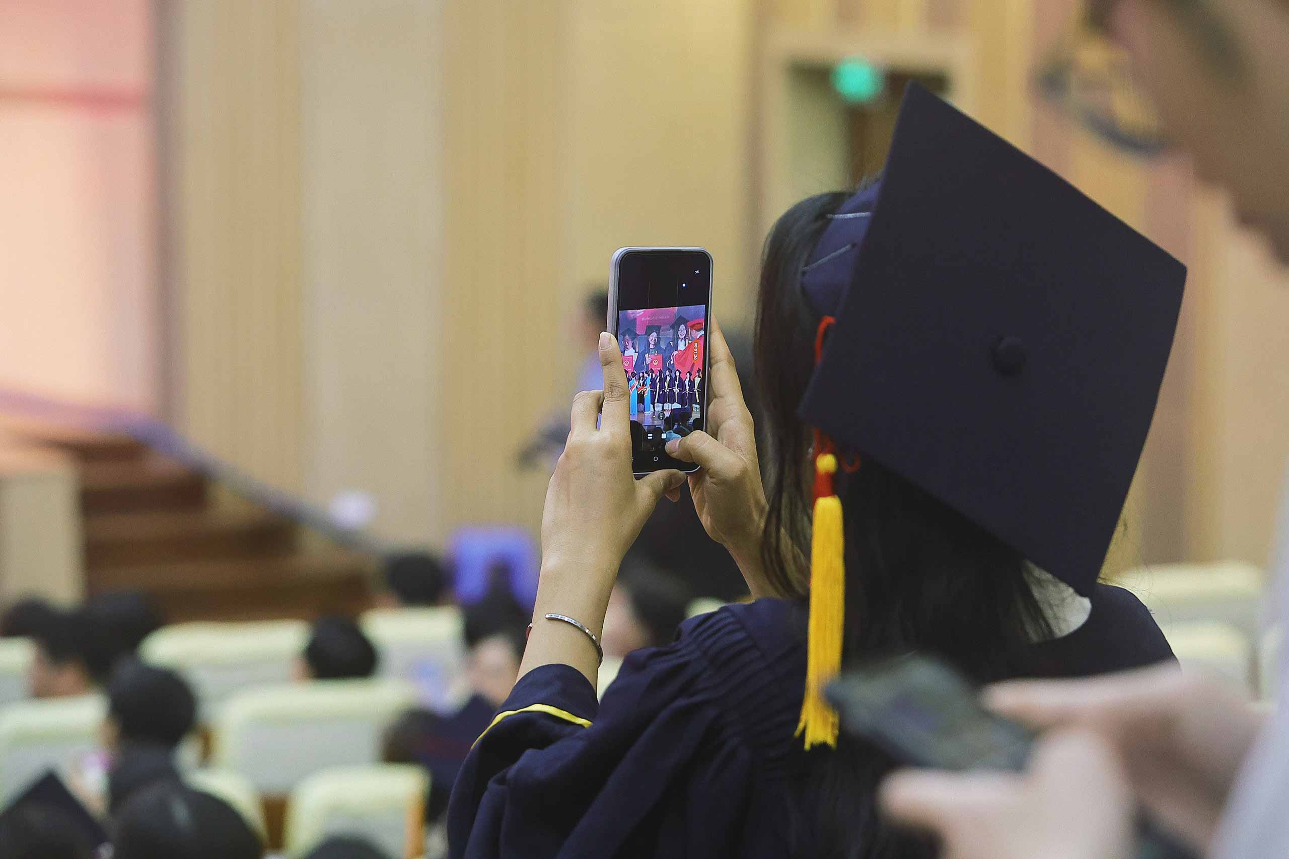 Một sinh viên Trường Đại học Sư phạm Hà Nội lưu lại khoảnh khắc khi người bạn của mình lên sân khấu nhận bằng tốt nghiệp. 