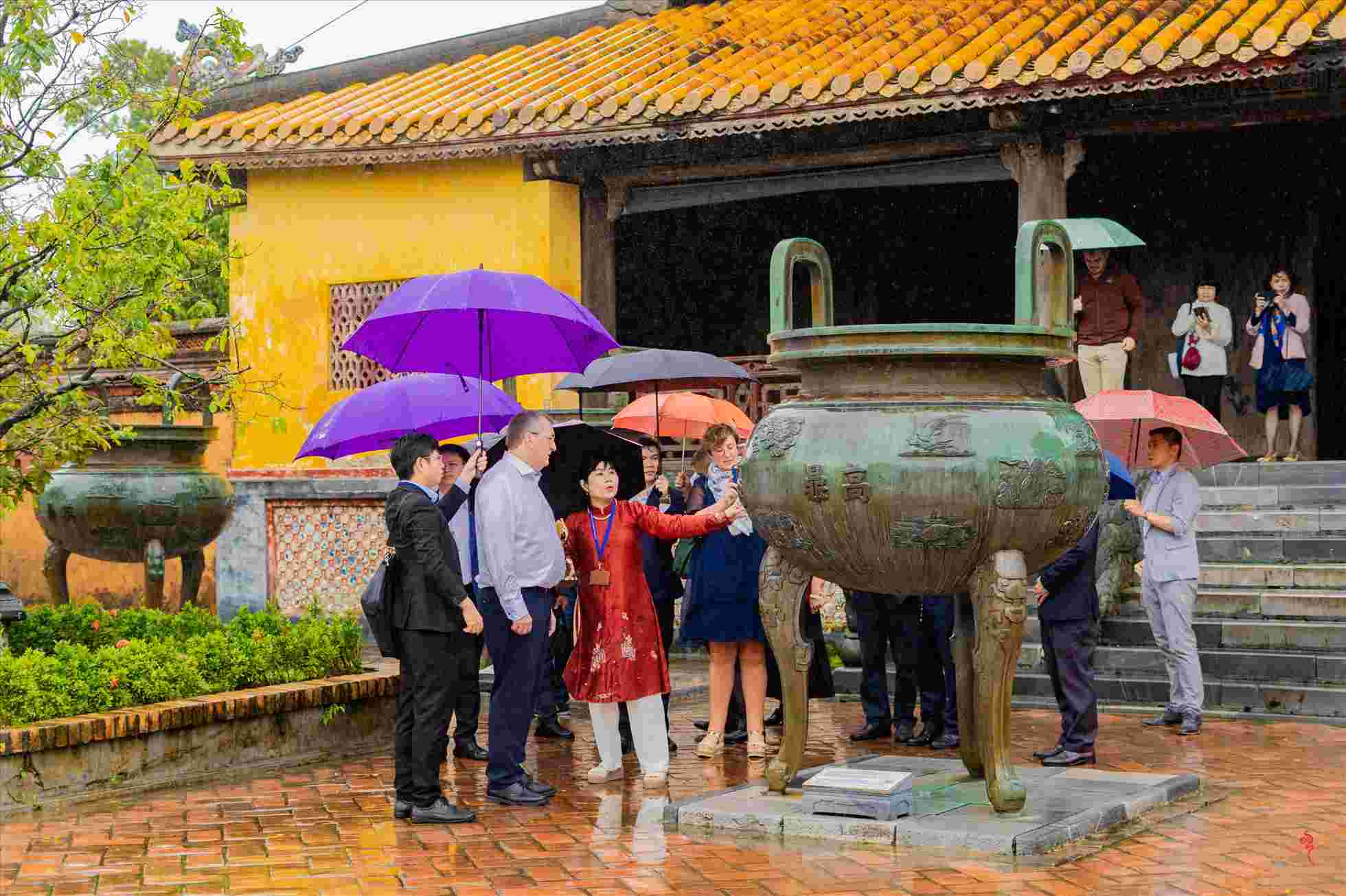 Đoàn khách tham quan Đại Nội Huế dưới trời mưa. Ảnh: Quảng An