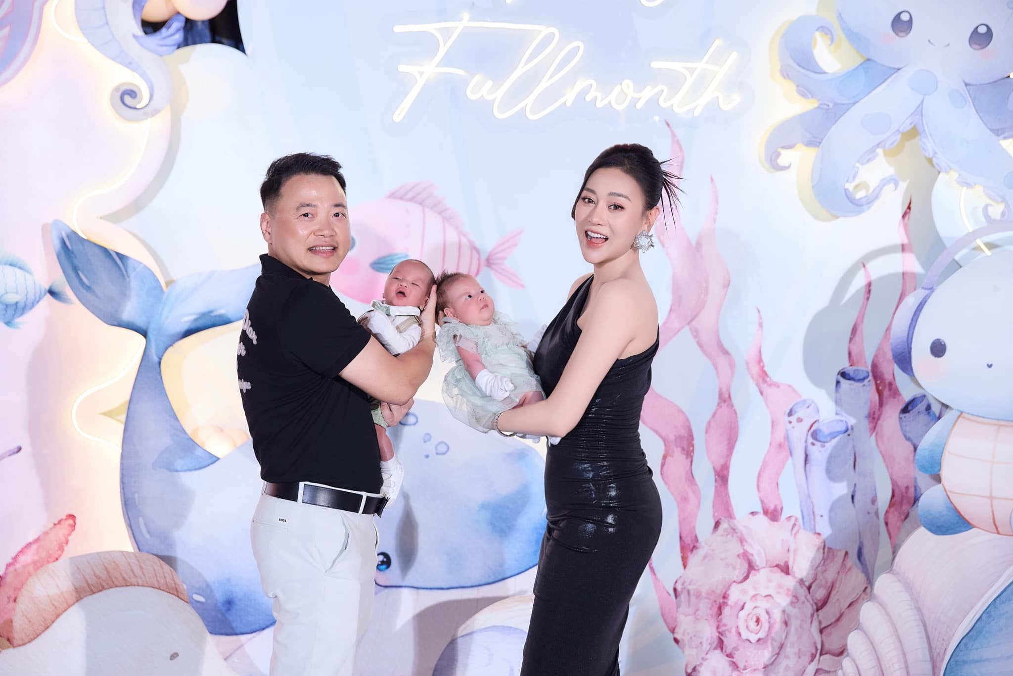 Phương Oanh và Shark Bình bế cặp sinh đôi trong tiệc đầy tháng. Ảnh: Facebook nhân vật