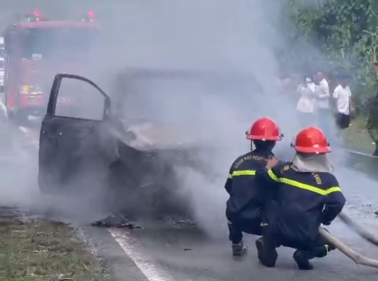 Lực lượng chữa cháy khống chế lửa phát ra từ chiếc xe ôtô 7 chỗ vừa đổ đèo Khánh Lê. Ảnh: P.Linh
