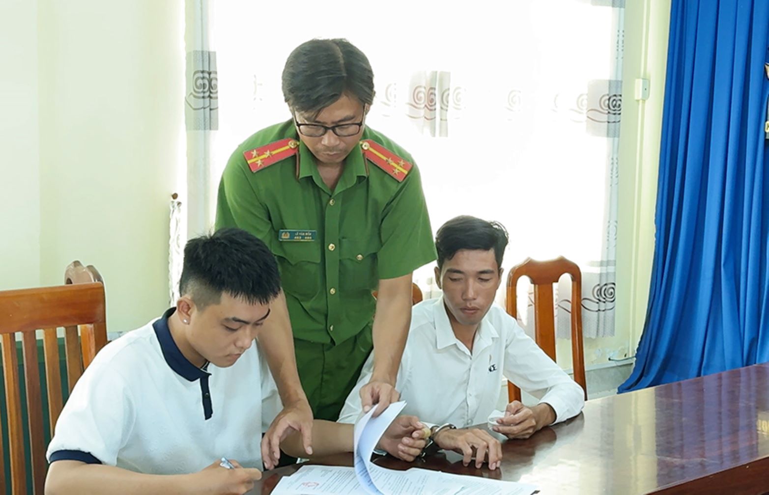 Bị can Hậu và Thanh (trái sang) ký nhận các Quyết định và Lệnh bắt tạm giam. Ảnh: Vũ Tiến