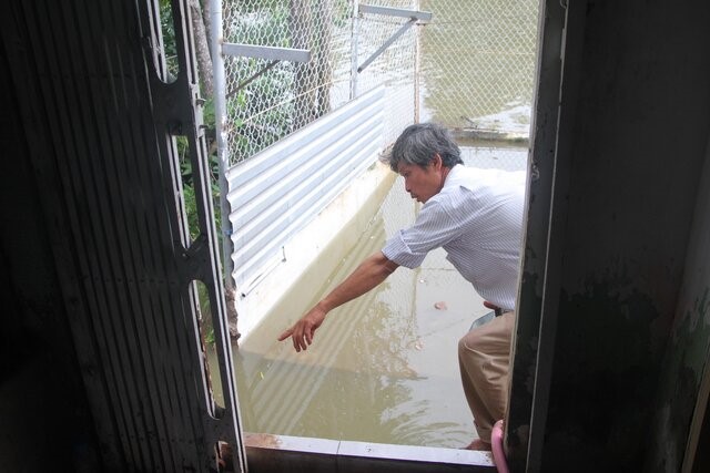 Người dân chỉ phần còn lại của căn nhà sau khi đã sạt lở xuống sông Bạc Liêu - Cà Mau. Ảnh: Nhật Hồ