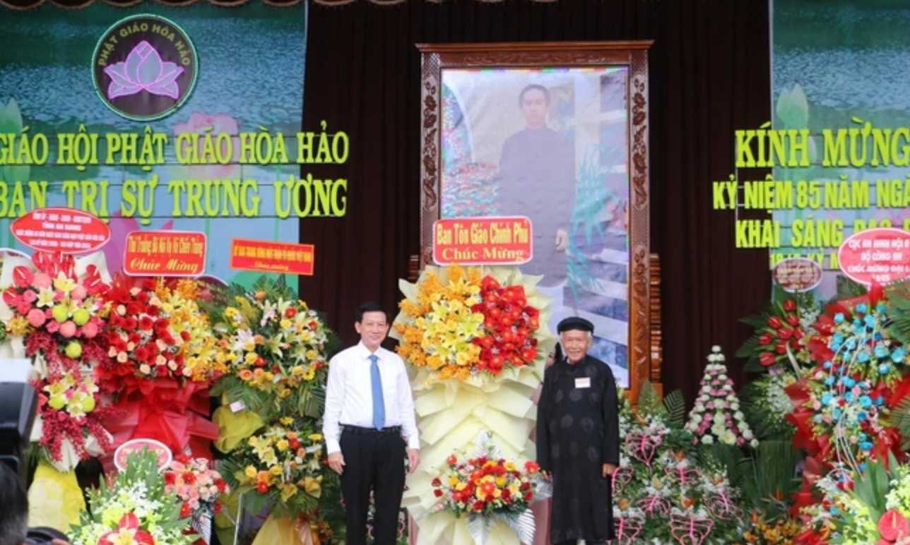 Phó trưởng Ban Tôn giáo Chính phủ Nguyễn Ánh Chức (trái) tặng hoa, chúc mừng Đại lễ kỷ niệm 85 năm Ngày khai sáng đạo Phật giáo Hòa Hảo. Ảnh: TTXVN