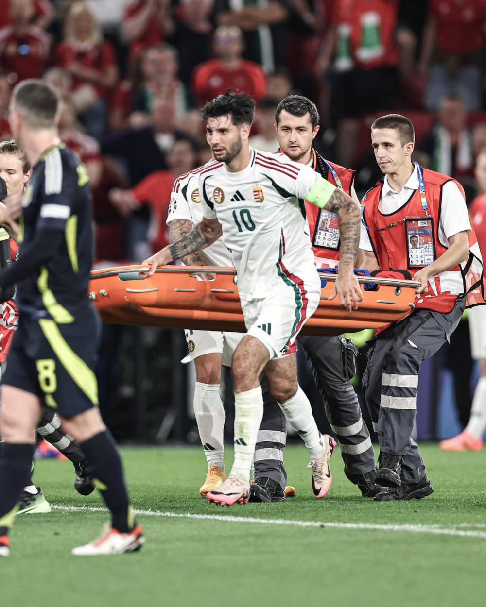 Dominik Szoboszlai hỗ trợ các nhân viên y tế đưa cáng vào sân giúp đồng đội. Ảnh: ESPN