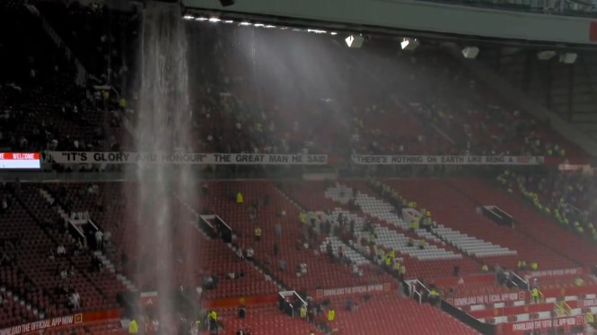 Mái che bị dột khiến mưa như trút nước xuống sân Old Trafford. Ảnh cắt từ video 