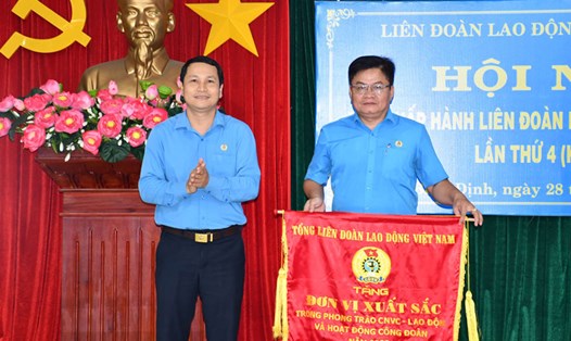 Chủ tịch LĐLĐ Bình Định Hà Duy Trung (trái) trao cờ thi đua xuất sắc năm 2023 của Tổng LĐLĐ Việt Nam cho Công đoàn Giáo dục Bình Định. Ảnh: Xuân Nhàn.
