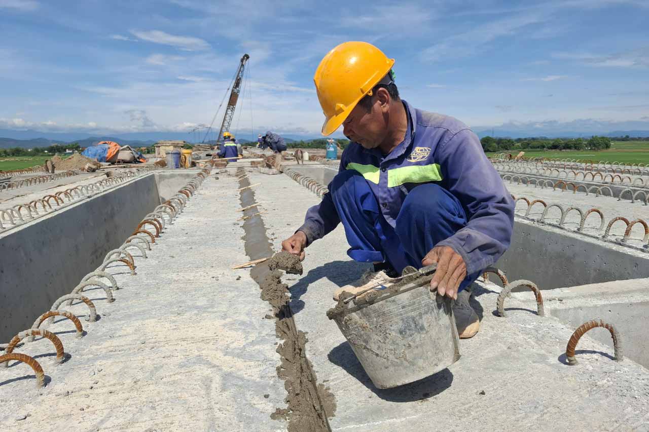 Công nhân Võ Văn Tình đang thi công  trét khe hở cánh dầm superT trên cầu. Ảnh: Trần Tuấn.