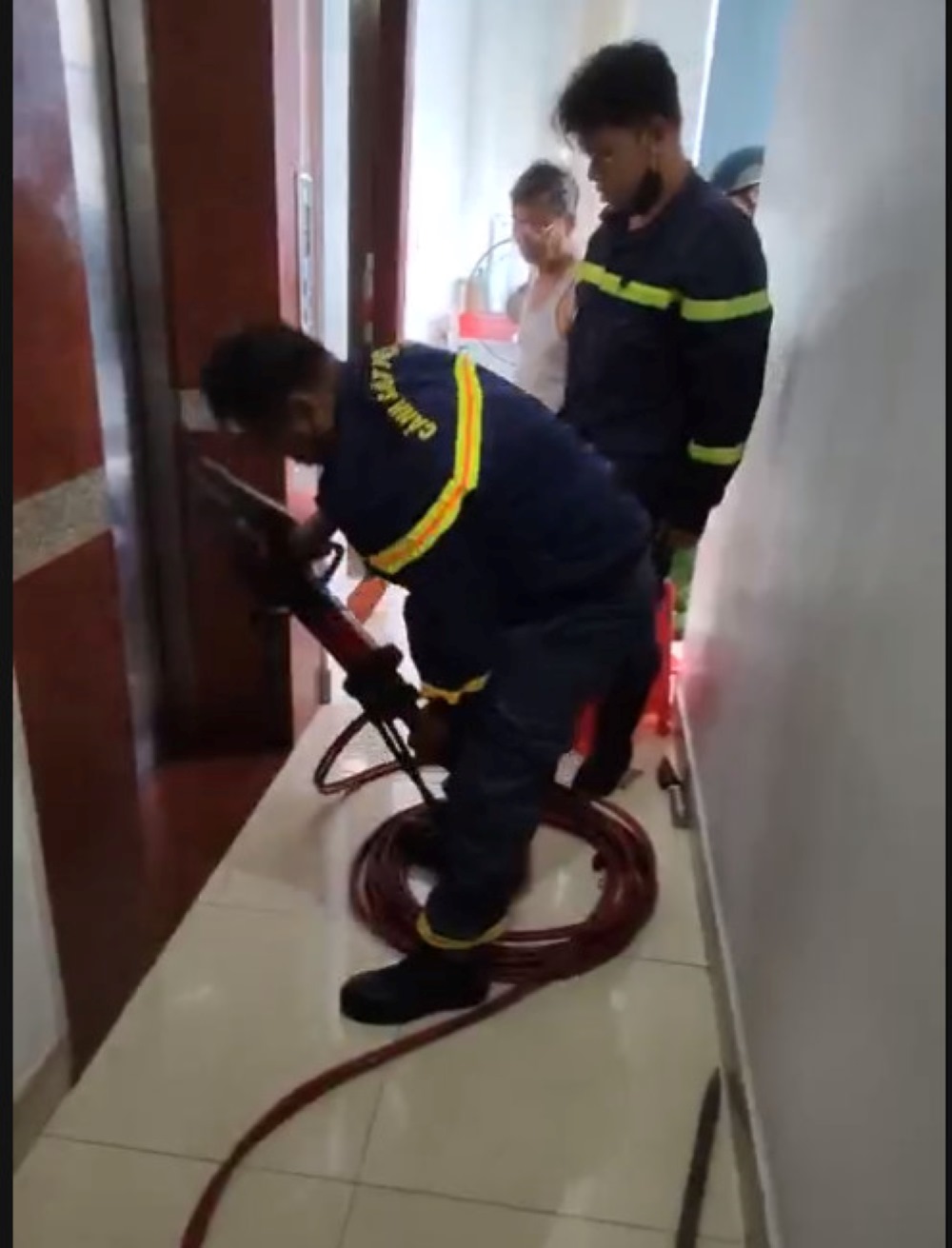 Lực lượng chức năng tiến hành sử dụng máy banh cắt thủy tách giữa 2 cánh cửa thang máy, tạo khoảng trống đưa các nạn nhân ra ngoài. Ảnh: Công an cung cấp