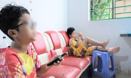Hai con của chị Nghi thường xuyên xem tivi, chơi điện thoại trong thời gian đợi mẹ đi làm về. Ảnh: Phong Linh