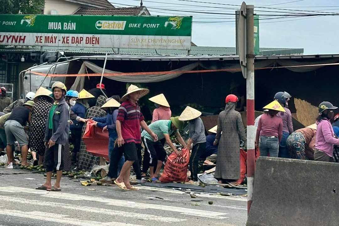 Người dân giúp tài xế gom trái cây đổ ra đường sau tai nạn. Ảnh: Trần Tuấn.