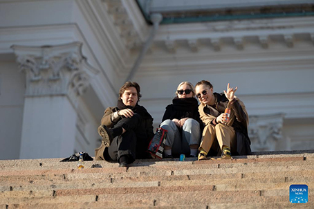 Người dân ngồi hóng mát trên bậc thang nhà thờ Helsinki ở Thủ đô Helsinki,  Phần Lan. Ảnh: Xinhua