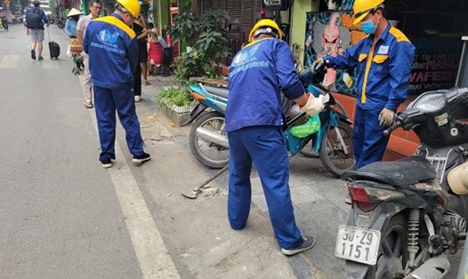Công nhân Xí nghiệp Thoát nước số 1 phá dỡ các bục, bệ bêtông làm đường dẫn vào nhà dân. Ảnh: Minh Hạnh 