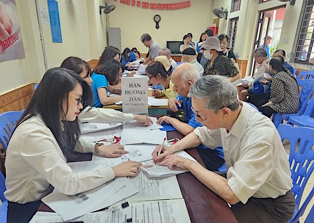Cán bộ BHXH TP Hà Nội phối hợp hướng dẫn người dân nhận lương hưu qua tài khoản cá nhân. Ảnh: BHXH Hà Nội