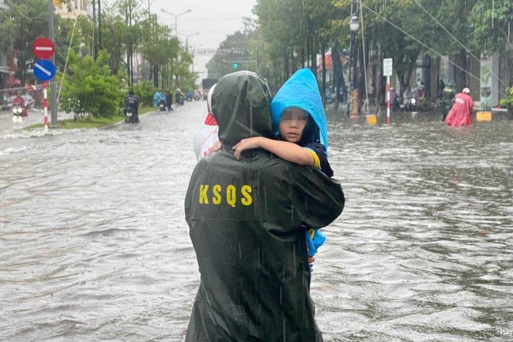 Cán bộ, chiến sĩ Bộ Chỉ huy Quân sự tỉnh Kiên Giang bế các em nhỏ qua khỏi đoạn đường ngập sâu. Ảnh: Phương Vũ