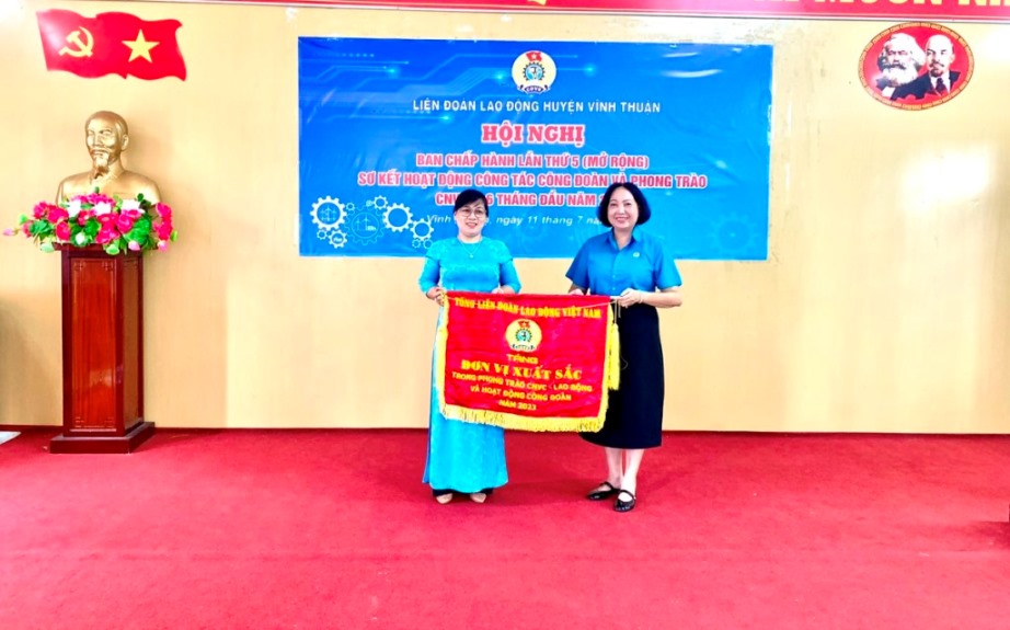 Bà Trang Thị Bích Ngọc (bìa phải) - Phó Chủ tịch LĐLĐ tỉnh tặng Cờ của Tổng LĐLĐ Việt Nam cho tập thể CĐCS Cựu chiến binh - LĐLĐ huyện. Ảnh: Kim Tiền