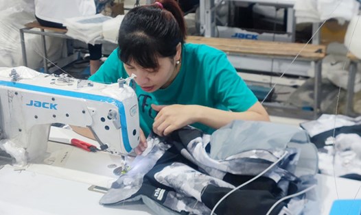 Thường xuyên ngồi cúi làm việc, chị Mai - nữ công nhân may mặc được chẩn đoán cong vẹo cột sống. Ảnh: Mạnh Cường.