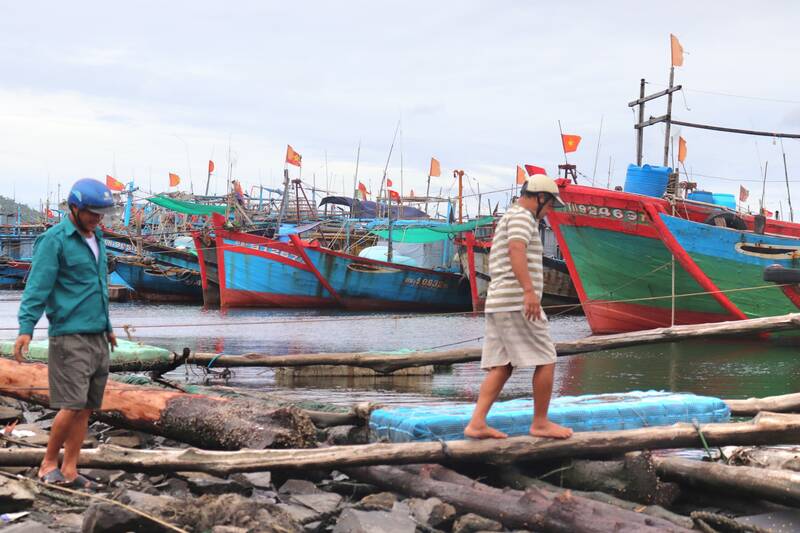 Mr. Tran Hoang (blue shirt) and other fishermen checked their boat while anchored at the port. Photo: Nguyen Linh