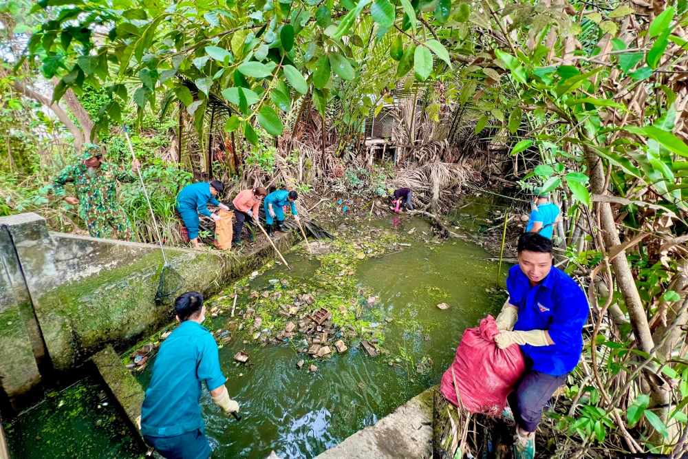 Ban điều hành khu phố và MTTQ Việt Nam xã Đa Phước cùng chung tay dọn rác trước khi xây dựng sân chơi. Ảnh: Minh Tâm.