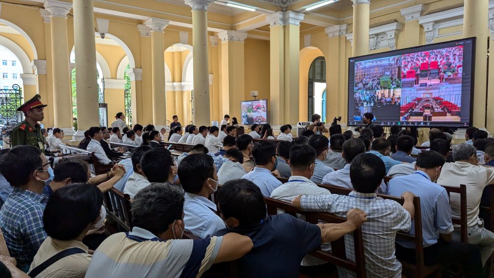 The defendants on bail and many lawyers watched the trial on a screen.