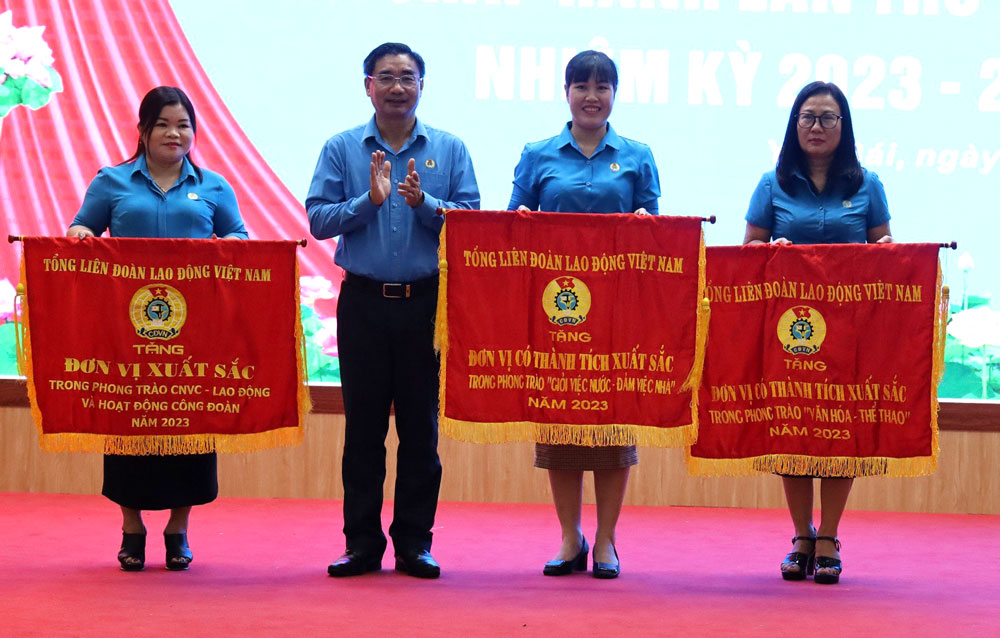 Được sự ủy quyền, ông Nguyễn Chương Phát - Chủ tịch LĐLĐ tỉnh Yên Bái trao cờ thi đua của Tổng LĐLD Việt Nam cho các tập thể. Ảnh: Bảo Nguyên