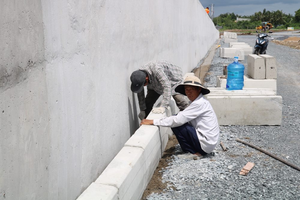  Trên công trường phía huyện Nhà Bè, nhiều máy móc, công nhân thi công đồng loạt các hạng mục như bó vỉa, đường dân sinh, đường dẫn cầu,... thuộc gói thầu xây dựng phần cầu và đường dẫn phía mố M1.