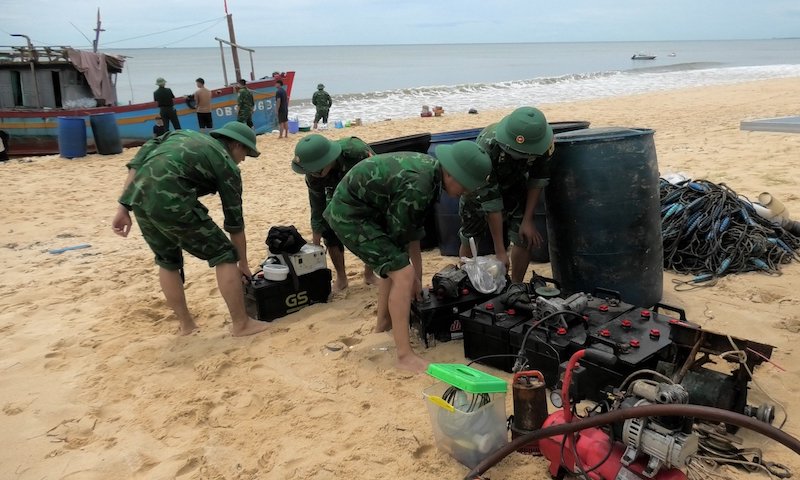 Lực lượng chức năng cùng gia đình mang vật chất và trang thiết bị lên bờ. Ảnh: Bộ đội Biên phòng