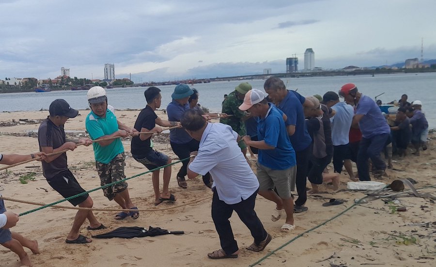 Tàu cá gặp nạn được lực lượng chức năng và người dân kéo vào bờ. Ảnh: Bộ đội Biên phòng