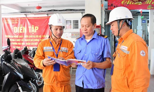 Người dân thuộc quận Cầu Giấy nhận “Sổ tay phòng cháy chữa cháy”. Ảnh: EVNHANOI.