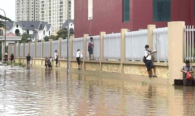 Nước ngập sâu, nhiều người dân phải trèo rào di chuyển. Ảnh: Lâm Phú