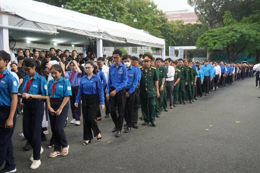 Người dân chờ vào trong Hội trường Thống Nhất viếng Tổng Bí thư dưới cơn mưa chiều 25.7. Ảnh: Anh Tú