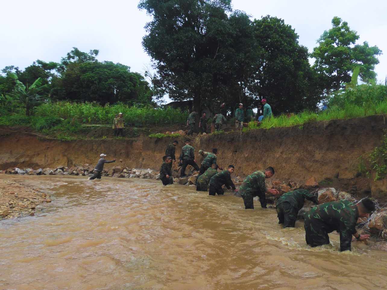 Ông Nguyễn Đình Thành - Phó Chủ tịch UBND xã Văn Lem cho biết: “Với sức của người dân trên địa bàn thì rất khó có thể đắp hết đoạn kè này. Tuy nhiên nhờ có sự góp sức của lực lượng vũ trang, công việc trở nên thuận lợi hơn rất nhiều. Bà con cũng phấn khởi khi nhận được sự hỗ trợ của các chiến sĩ trung đoàn 24 và trung đoàn 909.” Ảnh: Lê Nguyên 