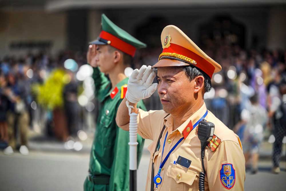 Các lực lượng an ninh trang nghiêm chào đoàn xe chở theo linh cữu Tổng Bí thư Nguyễn Phú Trọng qua khu vực phố Tràng Tiền, Hồ Gươm. Ảnh: Tô Thế