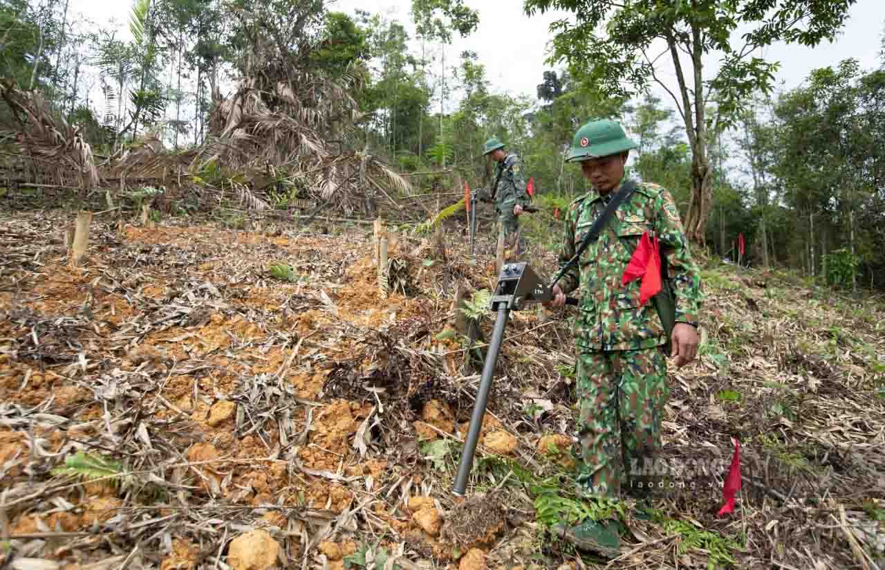 Các chiến sĩ thận trọng trong từng bước chân, thực hiện rà phá bom mìn vật nổ bằng máy dò, gỡ mìn đến độ sâu 30 cm, rồi lại tiếp tục dò, tìm đến độ sâu 3m. Những vị trí phát hiện vật nổ sẽ được cắm cờ đánh dấu.