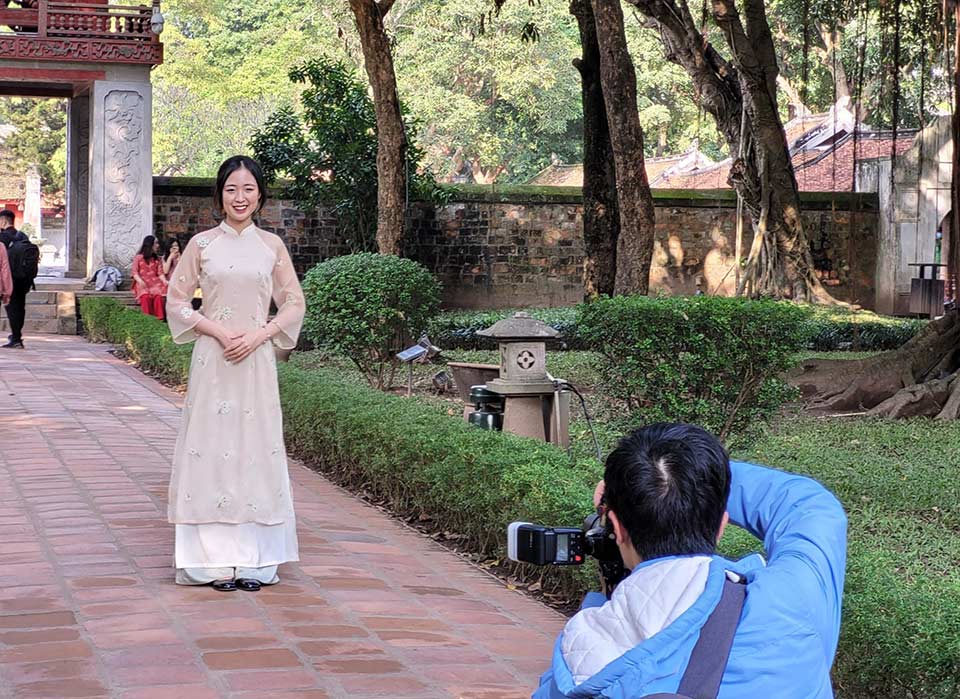 Tourists take photos wearing ao dai at the Temple of Literature - Quoc Tu Giam. Photo: Minh Ngoc