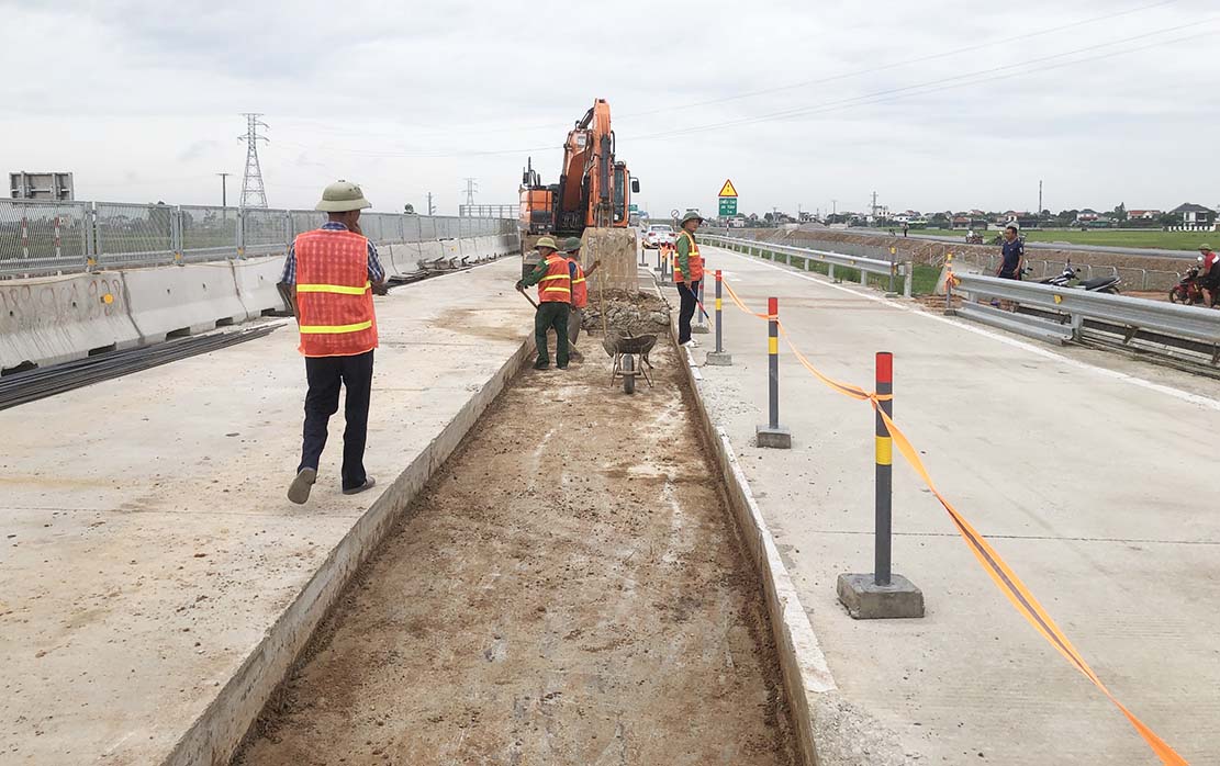 Workers peel off the poor concrete layer to build a toll island. Photo: Quang Dai