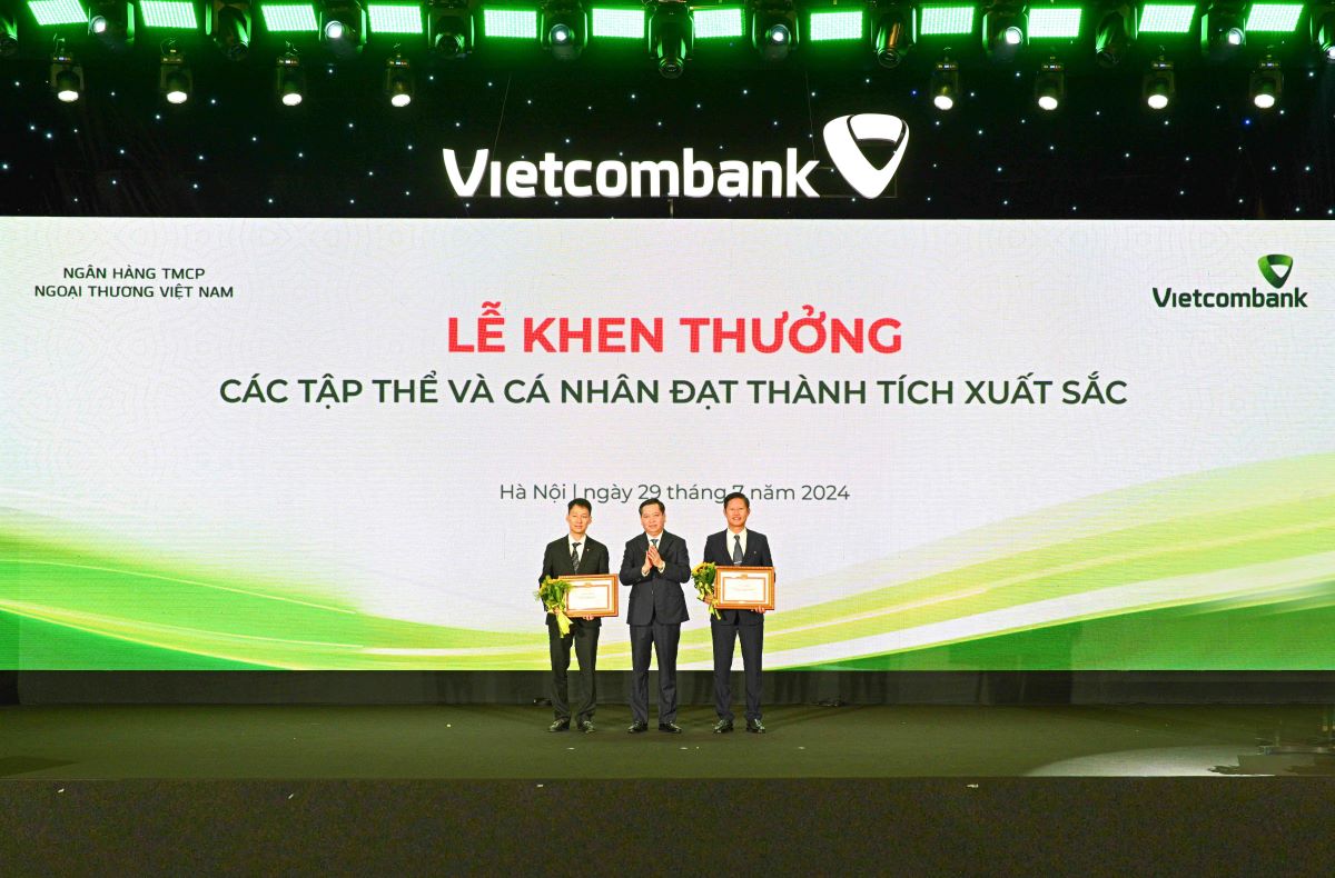 Comrade Nguyen Long Hai - Alternate Member of the Party Central Committee, Secretary of the Party Committee of the Central Business Bloc (DNTW) (center) presenting the Certificate of Merit and flowers to 2 party committees honored to receive the Certificate of Merit of the Party Committee of the Central Business Bloc. Photo: Vietcombank.