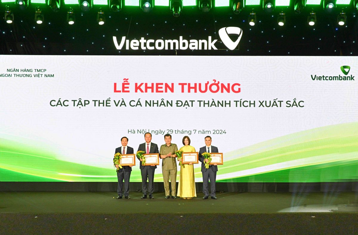 Comrade Nguyen Duc Phong - Permanent Deputy Secretary of the Party Committee of the Central Business Bloc (DNTW) (center) presenting the Certificate of Merit and flowers to 4 party members honored to receive the Certificate of Merit of the Party Committee of the Central Business Bloc. Photo: Vietcombank.