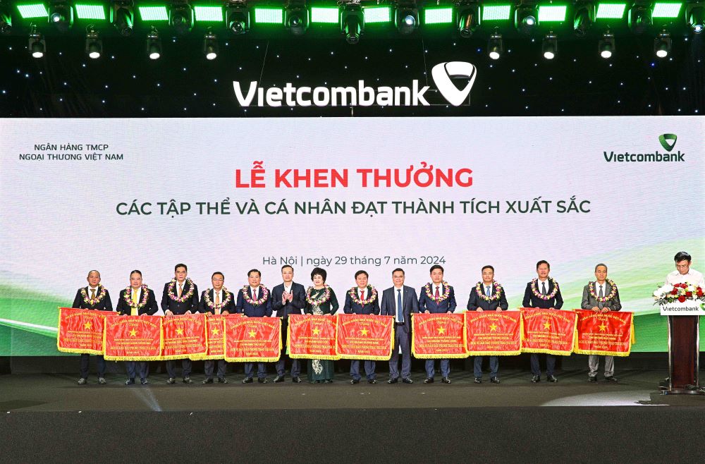 Comrade Pham Quang Dung - Member of the Party Affairs Committee, Deputy Governor of the State Bank of Vietnam (6th from left) presenting the Flag and Comrade Nguyen Thanh Tung - Chairman of the Board of Directors of Vietcombank (5th from right) presenting flowers to congratulate 11 collectives honored to receive the Emulation Flag of the State Bank of Vietnam. Photo: Vietcombank.