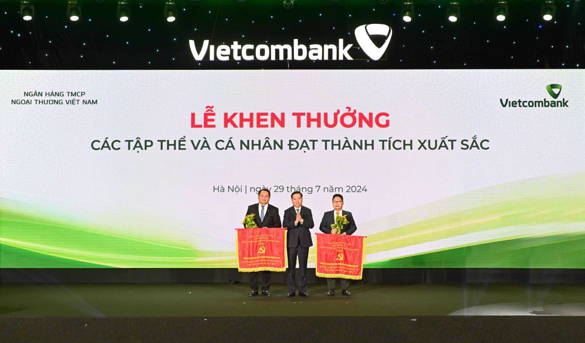 Comrade Nguyen Long Hai - Alternate Member of the Party Central Committee, Secretary of the Party Committee of the Central Business Bloc (DNTW) (center) presenting the Flag and flowers to 2 party committees honored to receive the Flag of the Party Committee of the Central Business Bloc. Photo: Vietcombank.