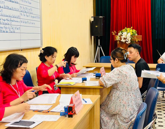 Giáo viên Trường Tiểu học Hồng Hà (quận Hoàn Kiếm, Hà Nội) hỗ trợ phụ huynh đăng ký tuyển sinh đầu cấp. Ảnh: Vân Trang