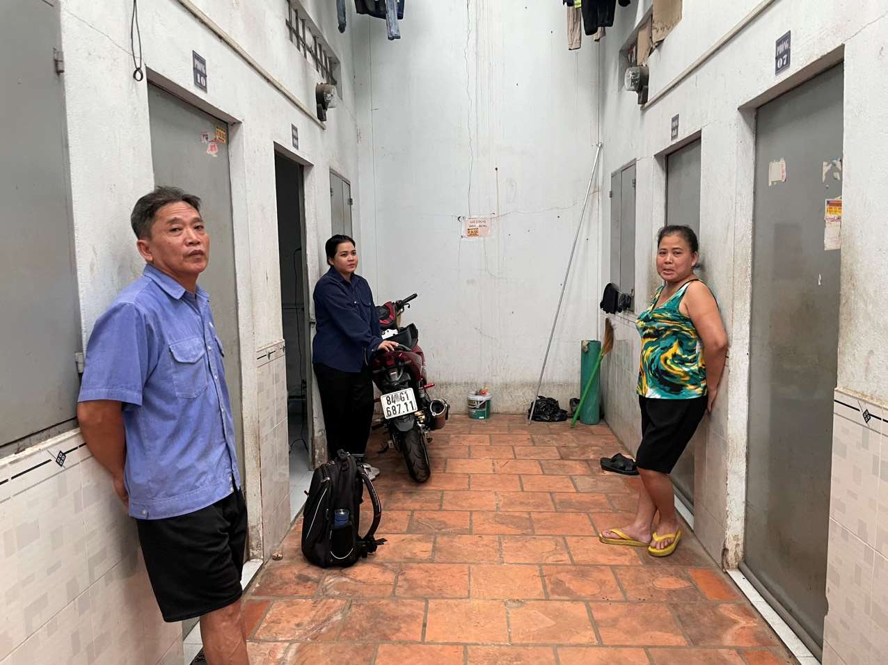 Workers whose wages are delayed stand sadly in front of the motel room door. Photo: Dinh Trong