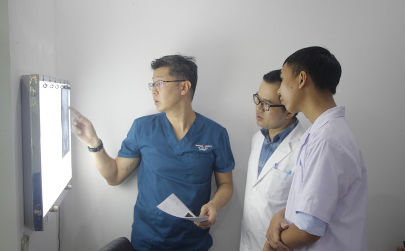 Thạc sĩ-Bác sĩ Đỗ Văn Hiếu (giữa) cùng chuyên gia y tế Singapore thảo luận trường hợp sỏi tiết niệu cho một bệnh nhân. Ảnh: Sông Hàn