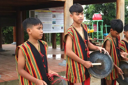 Trẻ em làng Đăk Mế tập đánh chiêng trong trang phục thổ cẩm. Ảnh: Thanh Tuấn  