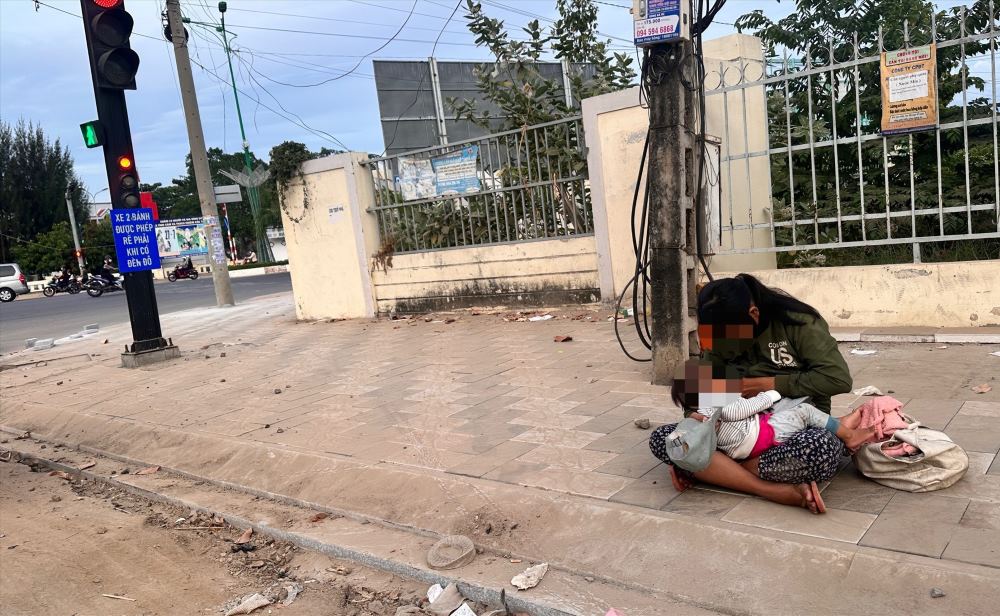 A woman holding a young child begging at a traffic signal intersection in Phan Thiết. Photo: Duy Tuấn