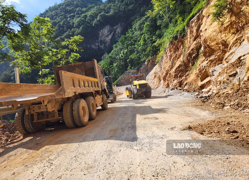 Workers are repairing the road surface and erecting guardrails.