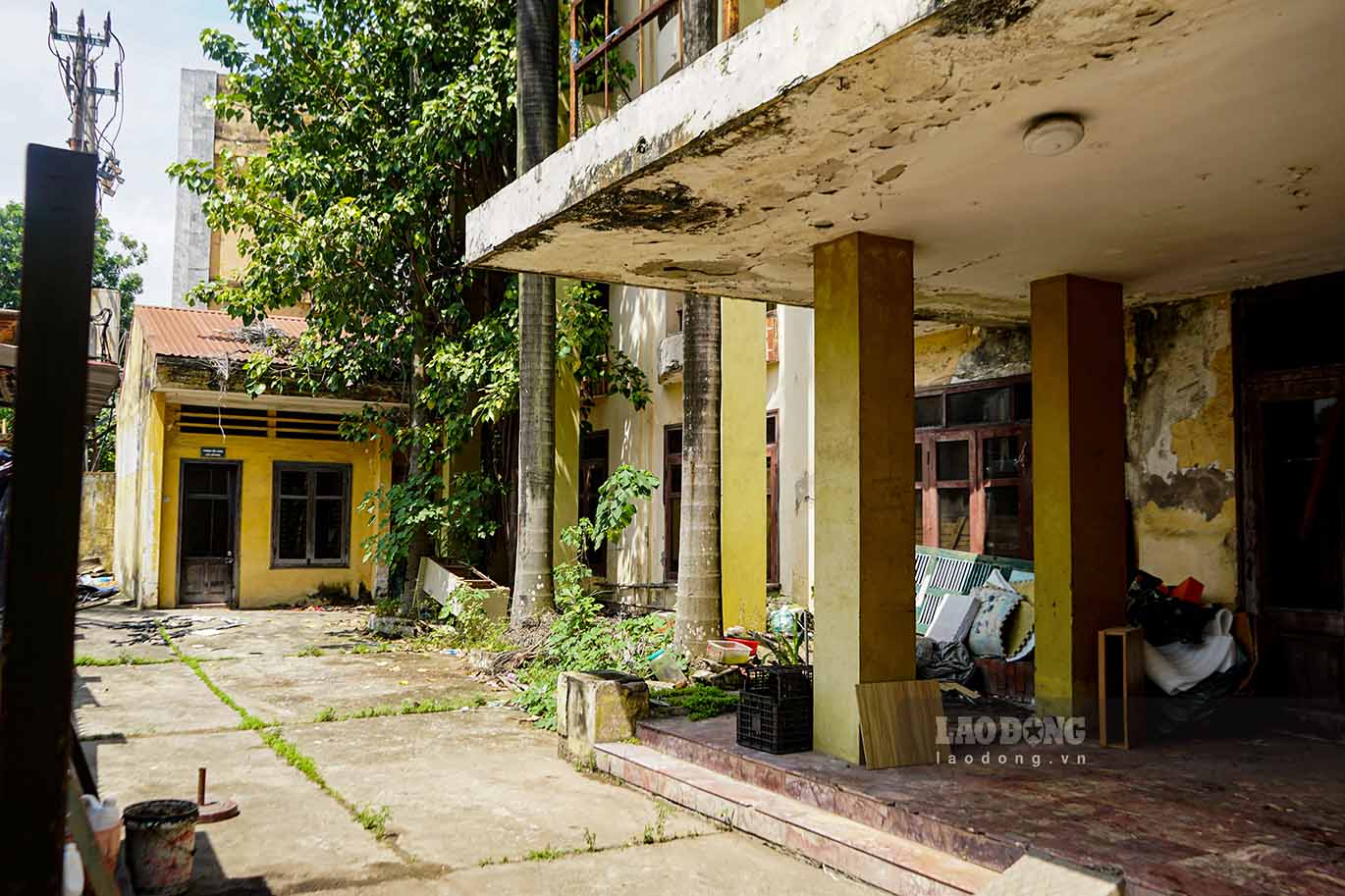 The current state of the building shows signs of deterioration, with pieces of the wall peeling and covered in vines and weeds.